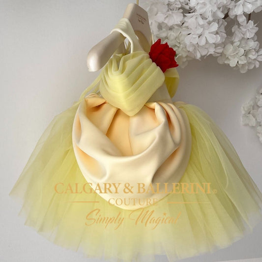 Shop belle from disney princesses inspired Yellow and white tutu dress with a red flower on a hanger, branded 'Calgary & Ballerini Couture'.