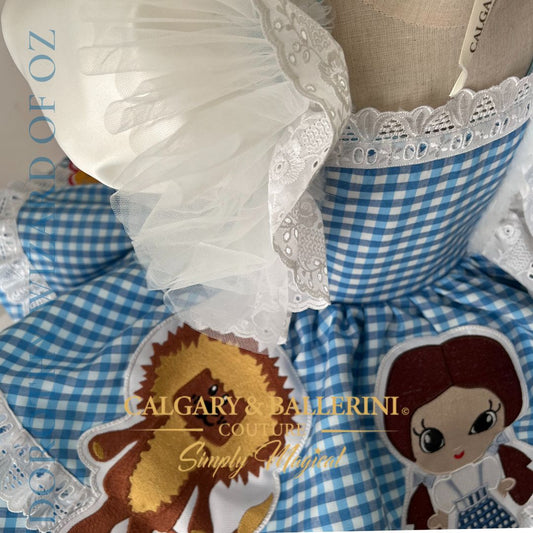 Where to order bespoke Dorothy Wizard of Oz first birthday outfit Calgary and Ballerini. Order a bespoke Dorothy Wizard of Oz first birthday dress, luxury artisan 3D character embroidery on blue gingham for showstopping party photos.