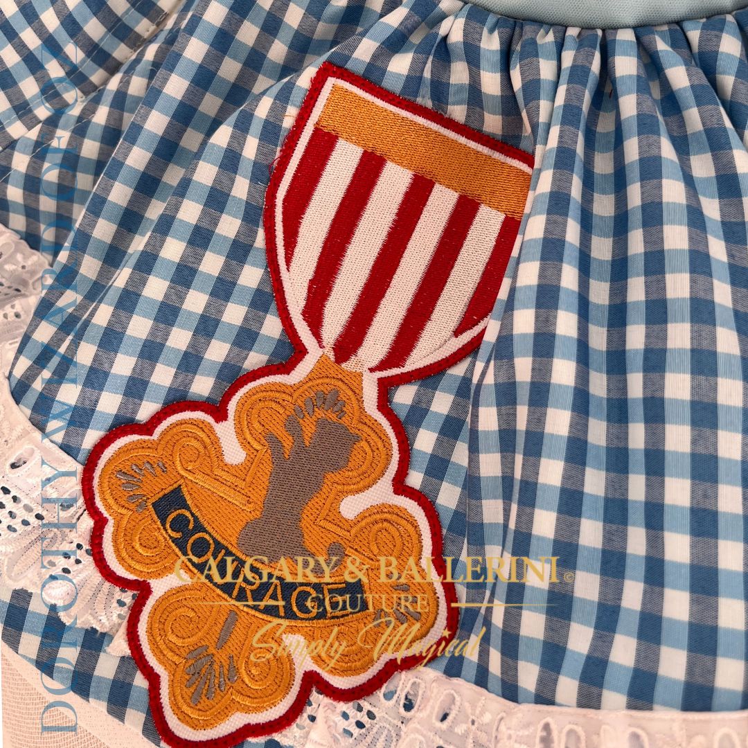 Shop heirloom Wizard of Oz first birthday dress, luxury blue gingham couture featuring Dorothy, Tin Man, and Lion embroidery for investment-piece wear.