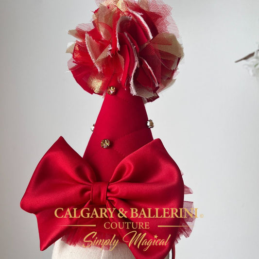 shop birthday party hat Red vintage circus theme headpiece with a large bow and floral details, featuring 'Calgary & Ballerini Couture' branding.