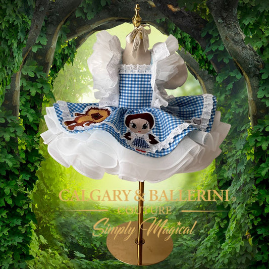 Buy our luxury Wizard of Oz birthday party dress in blue gingham, featuring handmade character embroidery of Dorothy, Lion, and Tin Man by Calgary and Ballerini.