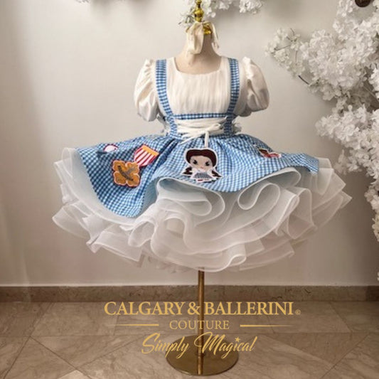 Order a bespoke Dorothy couture dress for first birthday parties, luxury handmade blue gingham gown with artisan character embroidery by Calgary and Ballerini.