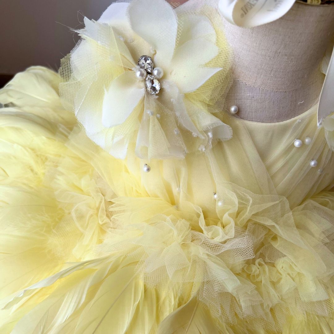 Order a bespoke yellow feather birthday dress and flower girl dress, featuring hand-stitched citrine feathers for a showstopping luxury look by Calgary and Ballerini