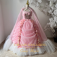 Pink Victorian-style ball gown with tulle fabric, floor-length cape, and rose details,