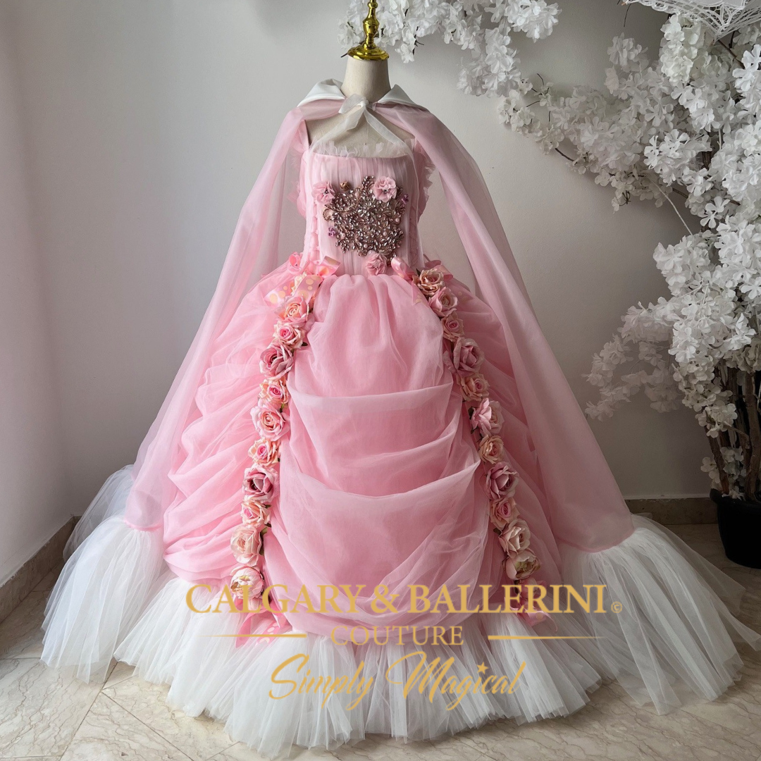 Pink Victorian-style ball gown with tulle fabric, floor-length cape, and rose details,