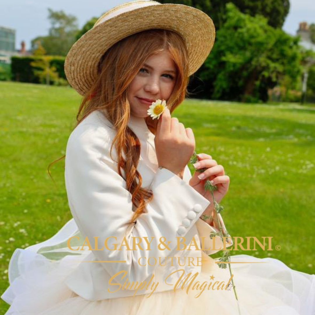 girl in a white dress and straw hat holding a flower in a park, with 'Calgary & Ballerini Couture' branding.