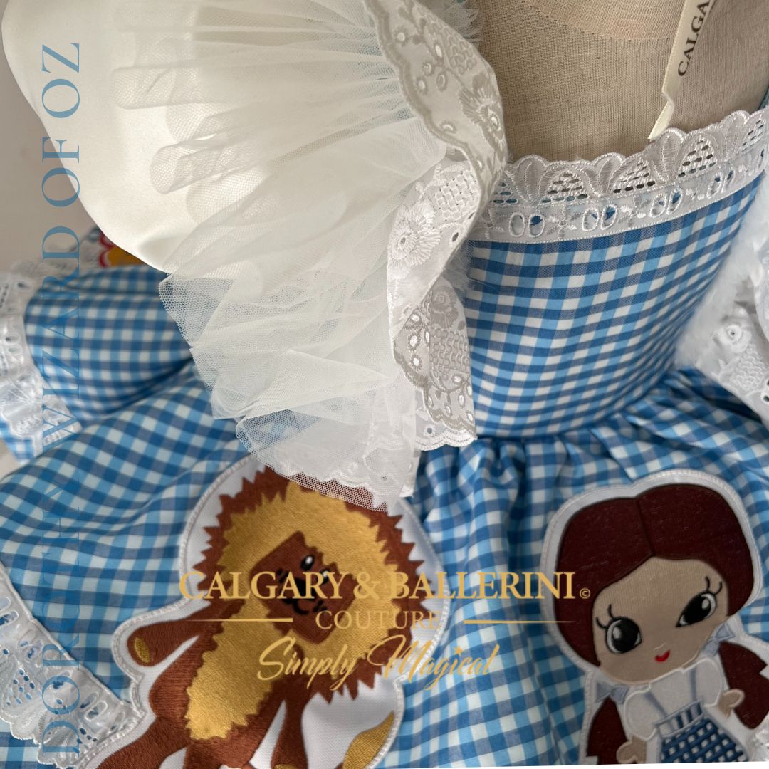 Where to order bespoke Dorothy Wizard of Oz first birthday outfit Calgary and Ballerini. Order a bespoke Dorothy Wizard of Oz first birthday dress, luxury artisan 3D character embroidery on blue gingham for showstopping party photos.