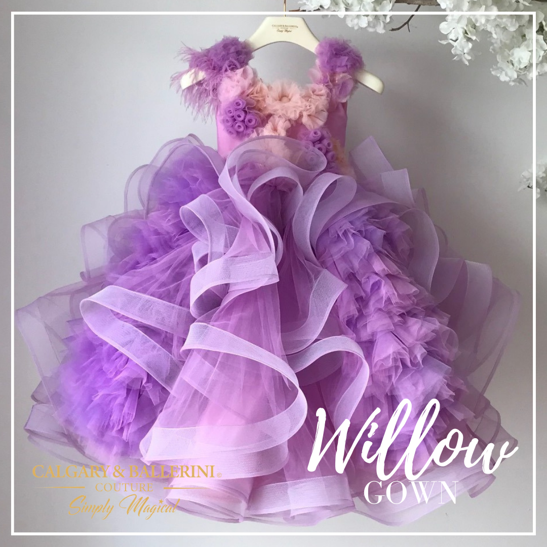 Willow is the must-have flower girl dress for any special occasion. Crafted with our signature layers of more than one hundred yards of horsehair tulle ruffles, this full floor length gown offers boundless volume and the perfect 'fluff' effect. Make a statement in violet with flower appliques on its bodice and elegant feather detail along its side sleeves 