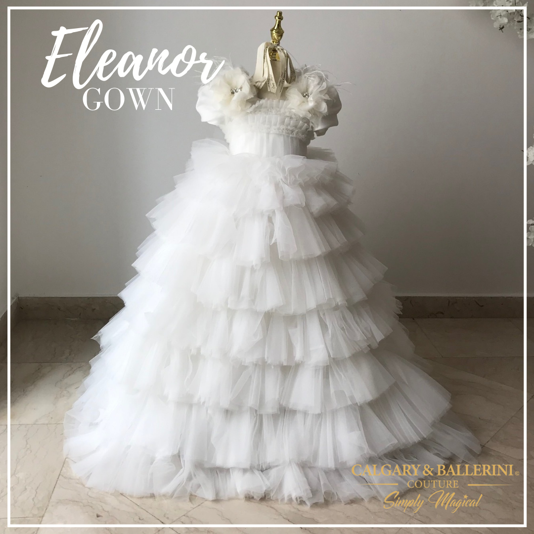 This beautiful dress is perfect for any special occasion, including first communion or serving as a flower girl. The floor-length tulle skirt is adorned with handmade organza flowers, each of which has a sparkling rhinestone center. 