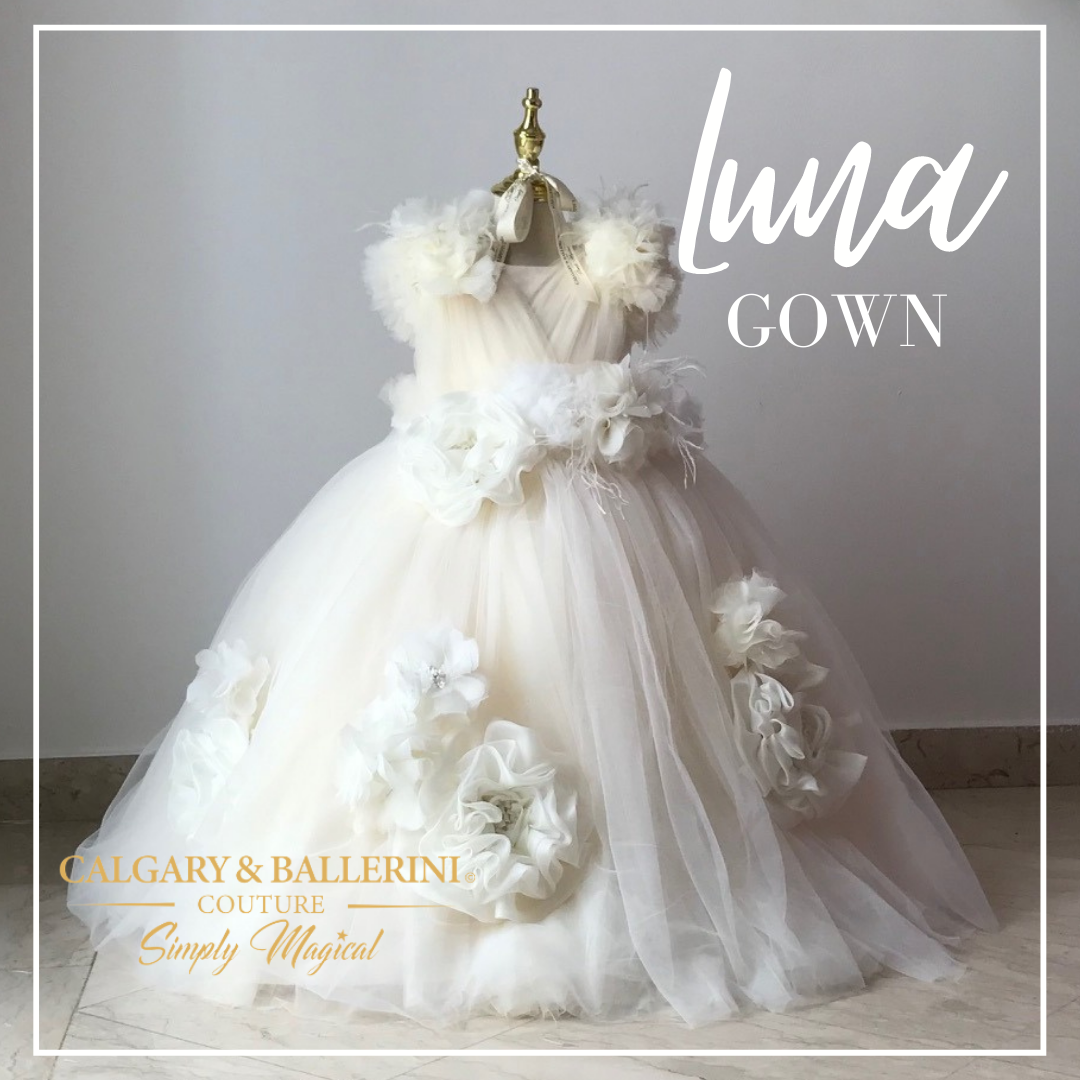 Featuring ivory-hued tulle and organza with a tumbled effect, the Luna gown is an exquisite flower girl dress for any special occasion. The pleated bodice and ruffle cap sleeves add a subtle hint of whimsy to the full-volume skirt while the oversized ivory flower adds dramatic flair to this stunning ivory dress. Whether your little girl is attending her own special event or walking down the aisle as the flower gir